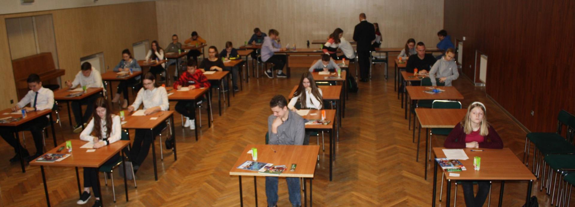 Zdjęcie przedstawia grupę osób, rozwiązujących test.