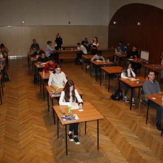 Zdjęcie przedstawia grupę osób, rozwiązujących test.
